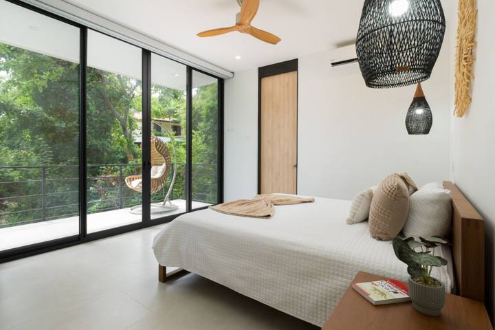 King bedroom with glass doors opening to a terrace with a hanging chair