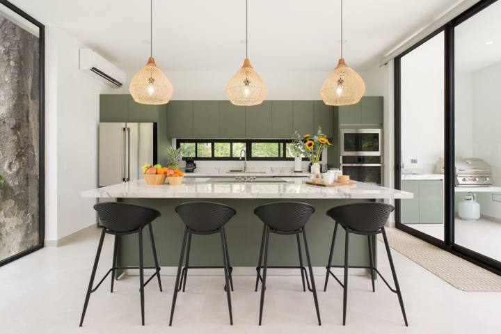 Kitchen with sage-green cabinets, marble island and woven pendant lights